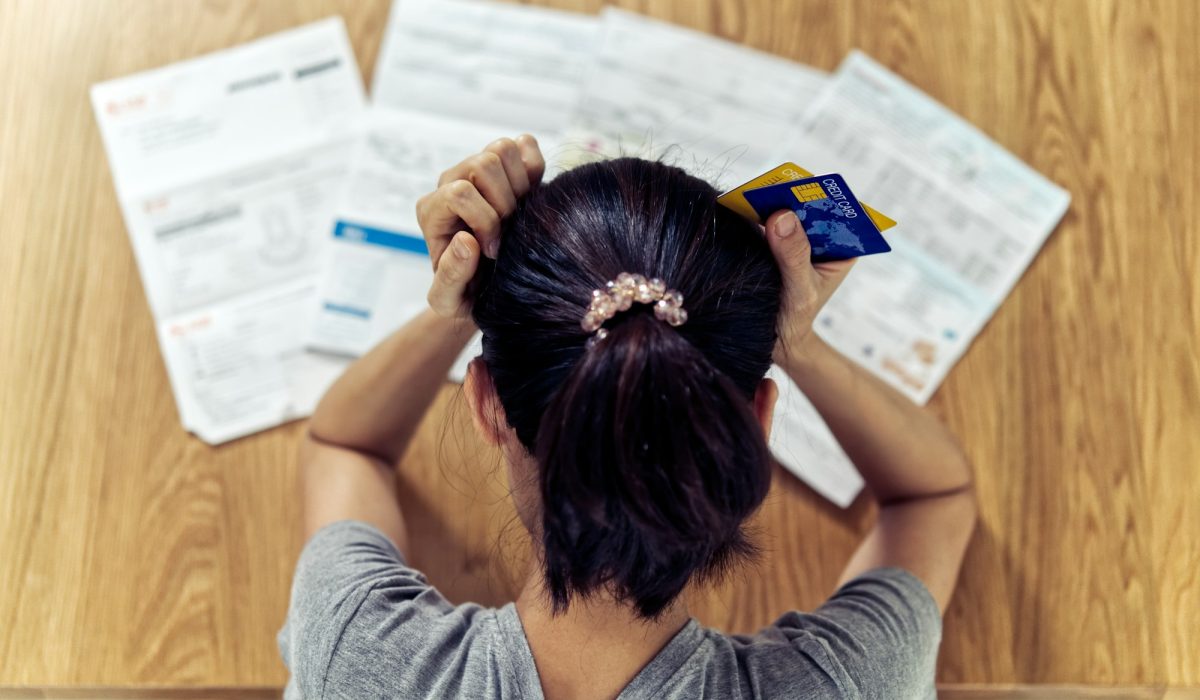Asian woman holding the head worry about find money to pay credit card debt and all loan bills.